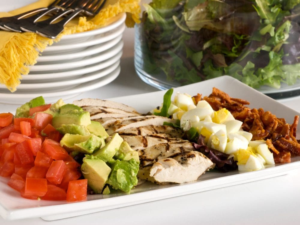 Chef Cari prepares her famous Cobb Salad with avocado, bacon, cherry tomatoes, and chicken.